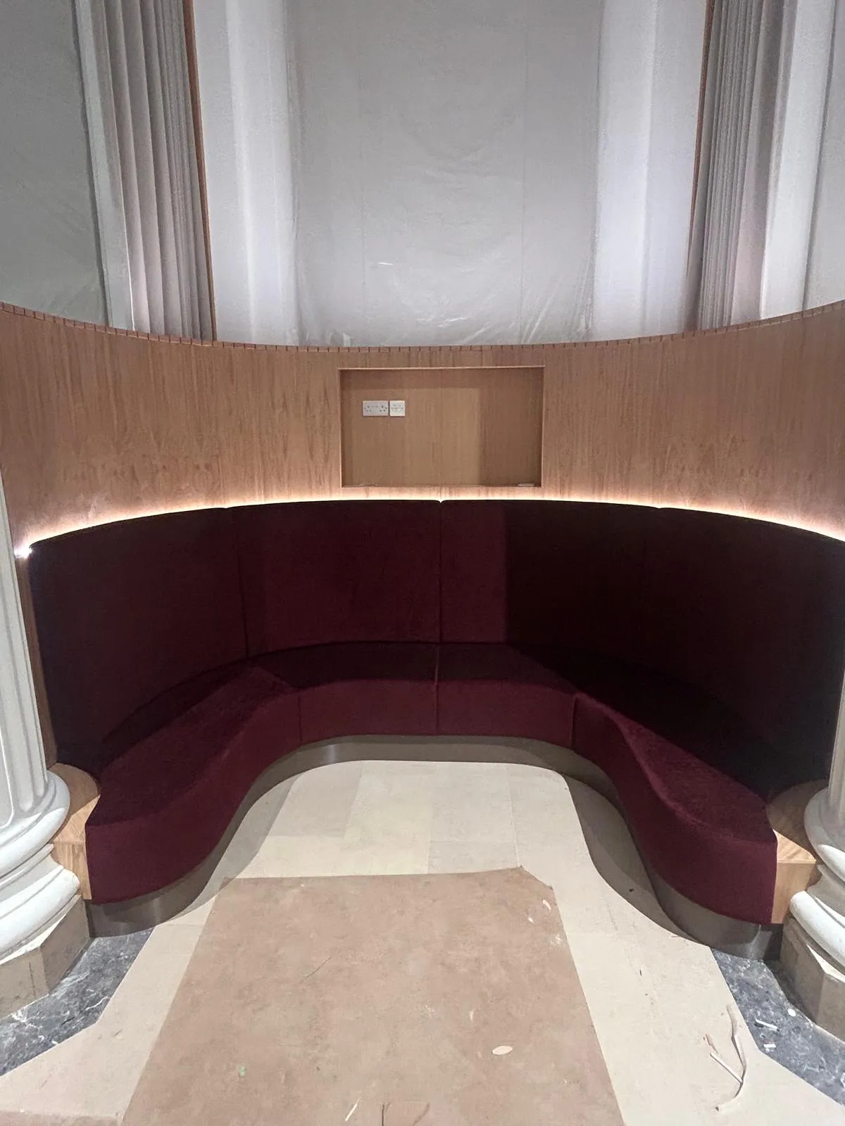 Curved oak booths between period columns: Finished, with the upholstery in and the lights on
