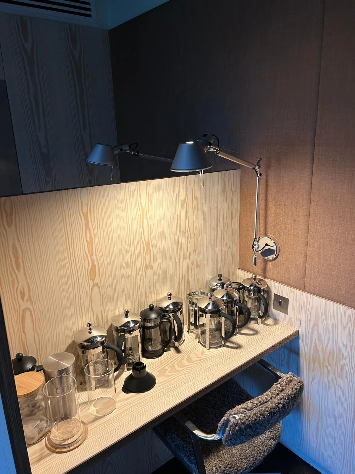 An office tea point with pale veneer panelling and a shelf of coffee pots